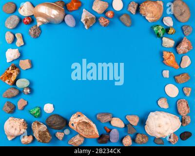 Cornice fotografica di conchiglie di mare e ghiaia su sfondo blu brillante con spazio per il tuo testo o foto Foto Stock