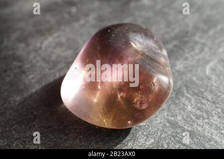 Ametrina tumbled ghiaia su sfondo grigio ardesia, illuminato dal sole Foto Stock