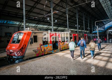 passeggiatori che camminano verso il treno a rossio stazione piattaforma ferroviaria a lisbona portogallo Foto Stock