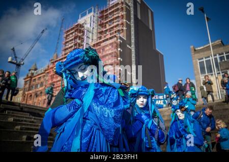 I Ribelli blu conducono centinaia di persone nella parata Blue Wave, organizzata da Extinction Rebellion, attraverso il centro di Glasgow per sensibilizzare i pericoli che Glasgow e il mondo si trovano ad affrontare a causa delle inondazioni causate dall'aumento dei livelli del mare e da un aumento delle tempeste. Foto Stock