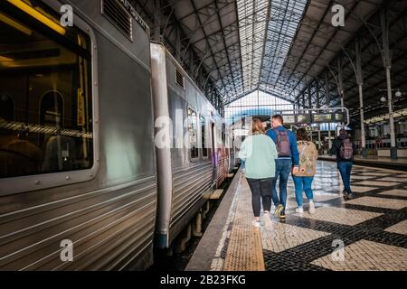 passeggiatori che camminano verso il treno a rossio stazione piattaforma ferroviaria a lisbona portogallo Foto Stock