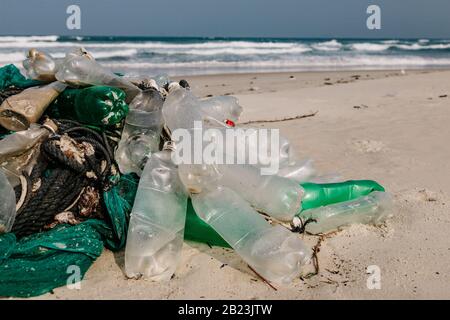 Bottiglie di plastica e altri rifiuti gettati sulla spiaggia sabbiosa, rifiuti sulla spiaggia di mare. Problema ecologico. Inquinamento ambientale. Spiaggia di sabbia sporca Foto Stock