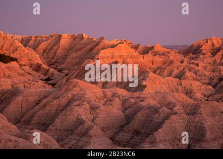 SD00250-00...SOUTH DAKOTA - Tramonto che dipinge l'arancia buttes lungo la strada del bordo di Sage Creek nel Parco Nazionale di Badlands. Foto Stock