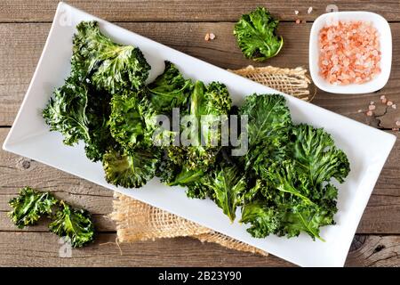 Piatto di sano biologico kale chip, vista dall'alto su rustico uno sfondo di legno Foto Stock