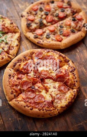 Composizione di tre diversi tipi di pizze sul tavolo di legno Foto Stock