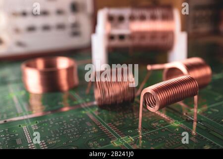 I cavi di rame ritorti si trovano in prossimità di un microcircuito verde. Concetto di fabbrica per la produzione di potenti misure oscillatorie Foto Stock