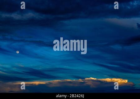 Spettacolare scenario notturno a strati blu con luna e piccole nuvole bianche Foto Stock