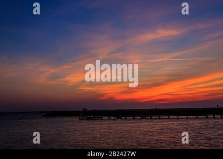 Tramonto vibrante paesaggio su acqua e sagome Foto Stock