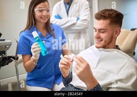 Il dentista consiglia ai prodotti dentali del paziente per l'igiene dei denti Foto Stock