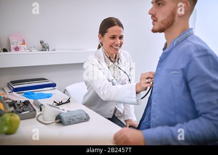 Il medico femminile con stetoscopio ascolta il cuore del paziente Foto Stock