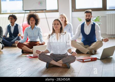 Donna d'affari che medita a work.group di colleghi di affari che meditano insieme al lavoro. Foto Stock