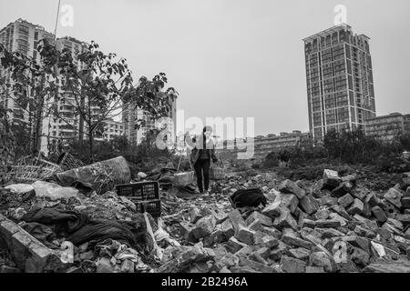 Scena di strada in un quartiere della città vecchia di Chongqing. Una donna che recupera i materiali da costruzione da una casa di demolizione, Chongqing, Cina Foto Stock