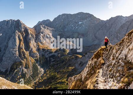 Alpinista con casco da arrampicata che corre su un ripido pendio di montagna, sentiero per Ehrwalder Sonnenspitze, Ehrwald, Mieminger Kette, Tirolo, Austria Foto Stock