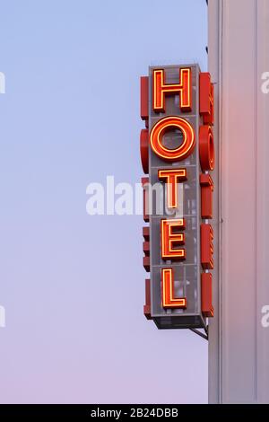 L'hotel neon firma sull'angolo dell'edificio contro il cielo del tramonto Foto Stock