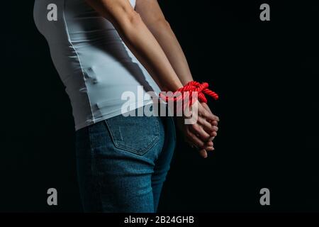 Vista corta della donna con le mani legate isolato sul nero Foto Stock