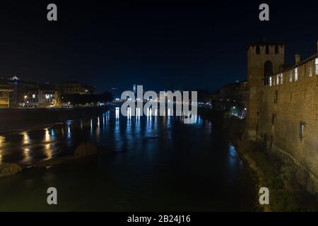 Vista di Verona e del fiume Adige dal ponte di Castelvecchio, conosciuto anche come il ponte Scaliger di notte, Italia Foto Stock