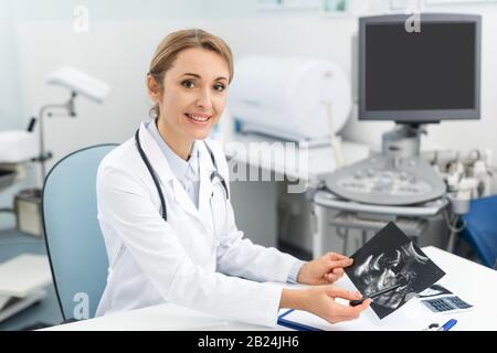 medico professionista di sesso femminile che mostra la scansione ecografica in clinica Foto Stock