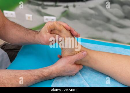 Il terapeuta osteopata effettua la manipolazione e il massaggio a piedi del paziente Foto Stock