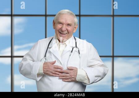 Il vecchio medico sta ridendo tenendo lo stomaco. Foto Stock
