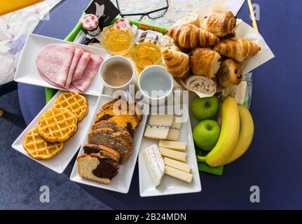 Bella colazione continentale servita per due persone e composta da croissant, panini, frutta, succo d'arancia, caffè, tè, diversi tipi di formaggio e Foto Stock