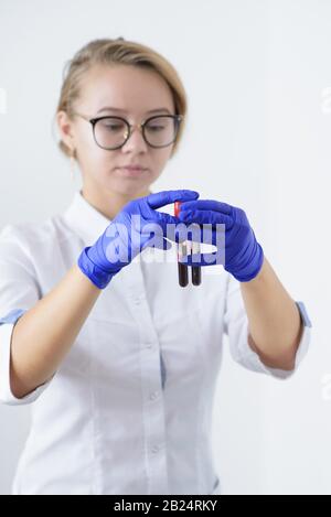 Medico che esamina due provette con campioni di sangue nelle mani. Il medico le mani che tiene la provetta di sangue nel laboratorio Foto Stock