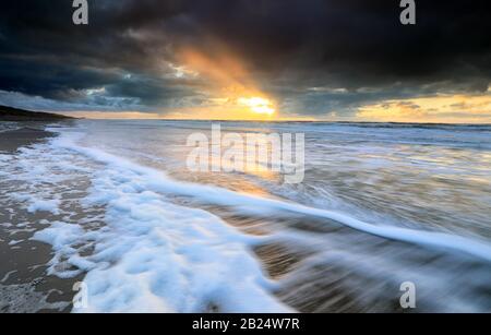 Tramonto spettacolare sulle onde del mare del Nord durante la tempesta Foto Stock