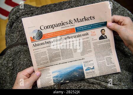 Parigi, Francia - 19 febbraio 2020: POV of Senior Hands holding Latest Financial Times Newspaper featuring Breaking news Alstom acquista Bombardier train unit Capital and Markets Foto Stock