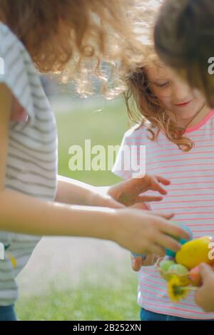 I bambini hanno raccolto le uova decorate nel cestino il giorno di Pasqua. Festa e concetto del bambino Foto Stock