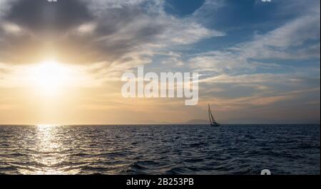 Silhouette vela barca a vela in mare aperto al tramonto. Monoscafo inclinato in serata. Avventura estiva di lusso, vacanza attiva nel Mar Mediterraneo Foto Stock