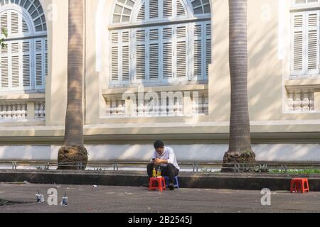 Saigon (ho Chi Minh City) Street scene - un uomo vietnamita bere uno sgabello sulla strada a Saigon, Vietnam, Sud-Est asiatico. Foto Stock