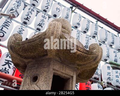 Lanterna di pietra e lanterne di carta all'esterno di un tempio a Tokyo, Giappone. Foto Stock