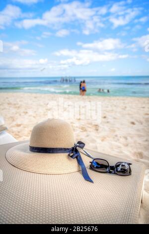 Tema vacanza con occhiali da sole e cappello in una spiaggia tropicale con mare e cielo blu. Spazio di copia. Foto Stock