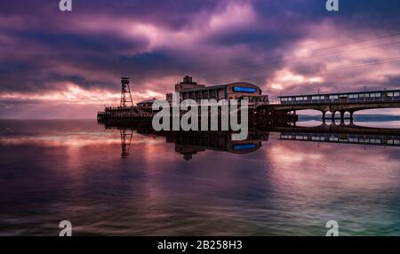 I cieli colorati sopra il Molo di Bournemouth si riflettono nell'acqua Foto Stock