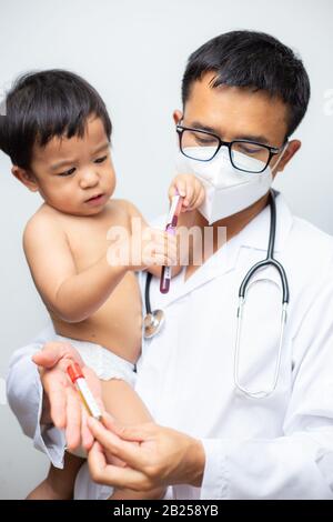 Il medico tiene il vaccino del vaccino di Covid-19 intube trasporta il bambino ragazzo sul concetto sano di fondo bianco Foto Stock