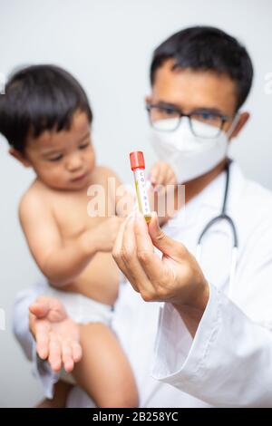 Il medico tiene il vaccino del vaccino di Covid-19 intube trasporta il bambino ragazzo sul concetto sano di fondo bianco Foto Stock