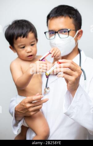 Il medico tiene il vaccino del vaccino di Covid-19 intube trasporta il bambino ragazzo sul concetto sano di fondo bianco Foto Stock