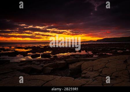 Il cielo si schiarisce dopo una tempesta di pioggia appena abbastanza a lungo per mostrare le profonde nuvole rosse e viola sulla costa sud del dorset jurassic Foto Stock