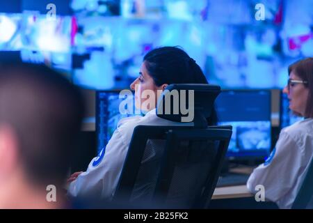 Nel sistema di controllo, camera operatore tecnico lavora presso la propria workstation con monitor multipli, guardia di sicurezza lavorando su più monitor. Foto Stock