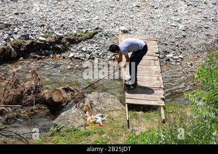 Uomo che pulisce un ruscello, raccoglie spazzatura, rifiuti da un ruscello. Hunedoara / Romania Foto Stock