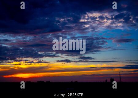 New Scenic 5 posti è vista sul bel cielo azzurro con soffici nuvole al tramonto e il paesaggio urbano in distanza. Foto Stock