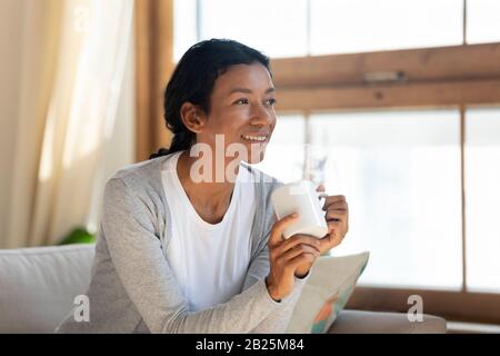 Donna biraciale sorridente guarda a distanza sognando Foto Stock