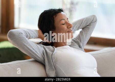 Calma donna biraciale rilassarsi sul divano prendere pisolino Foto Stock