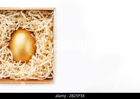Golden Egg in una scatola su uno sfondo bianco concetto di esclusività, scelta migliore, premio, sorpresa speciale, regalo costoso. Il concetto di minimalismo. Iso Foto Stock