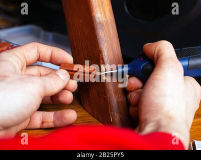 restauro di prodotti in legno. restauro e riparazione di trucioli su mobili con cera calda e saldatore. Foto Stock