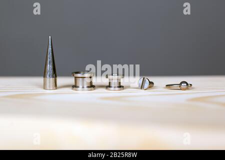 set di accessori per piercing su tavola di legno. Foto Stock