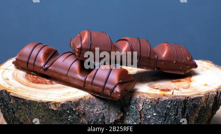 bastoncini di deliziosi dolci con cioccolato al latte su un supporto in legno su uno sfondo grigio. Foto Stock