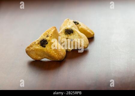 Ozney haman (orecchio di Haman) pasta Triangolare fatta di pasta croccante farcita. Cibo ebraico tradizionale per Purim. Situato su una superficie di legno Foto Stock