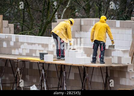 Cantiere, casa residenziale è in costruzione, muratori al lavoro, muratura una parete, su un ponteggio, alto, Foto Stock