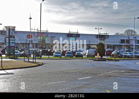 Una vista sulla strada di una fila di moderni negozi e parcheggio auto, al Talbot Green Retail Park, un tipico piccolo centro commerciale fuori città. Foto Stock