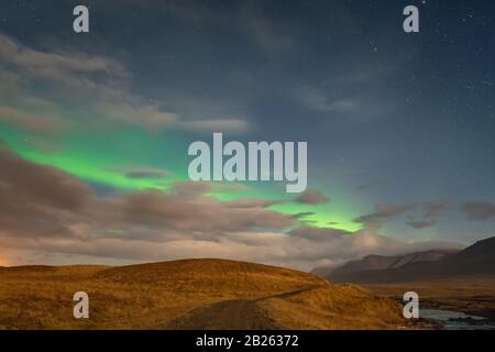 Aurora in Islanda luci settentrionali striscia luminosa in cielo durante la notte di luna piena Foto Stock